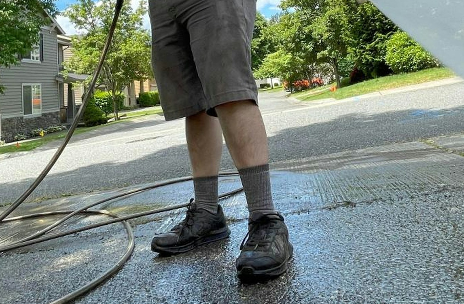 A pressure-washing wand rinsing a concrete driveway